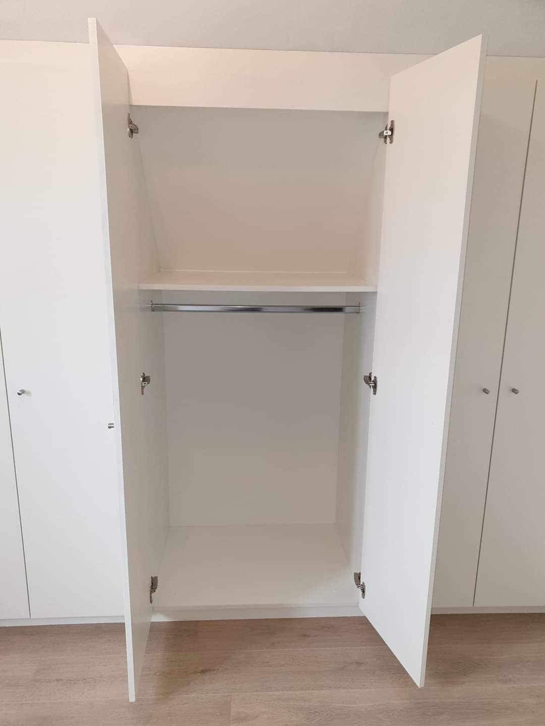 Witte maatkast met hangroede, deuren geopend