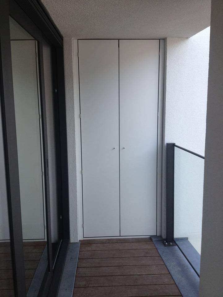 Hoge witte inbouwkast in een inkomhal met glaswand