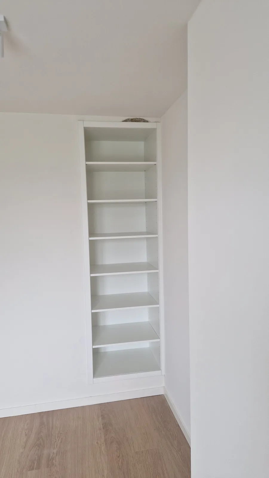 Smalle boekenkast tot aan het plafond