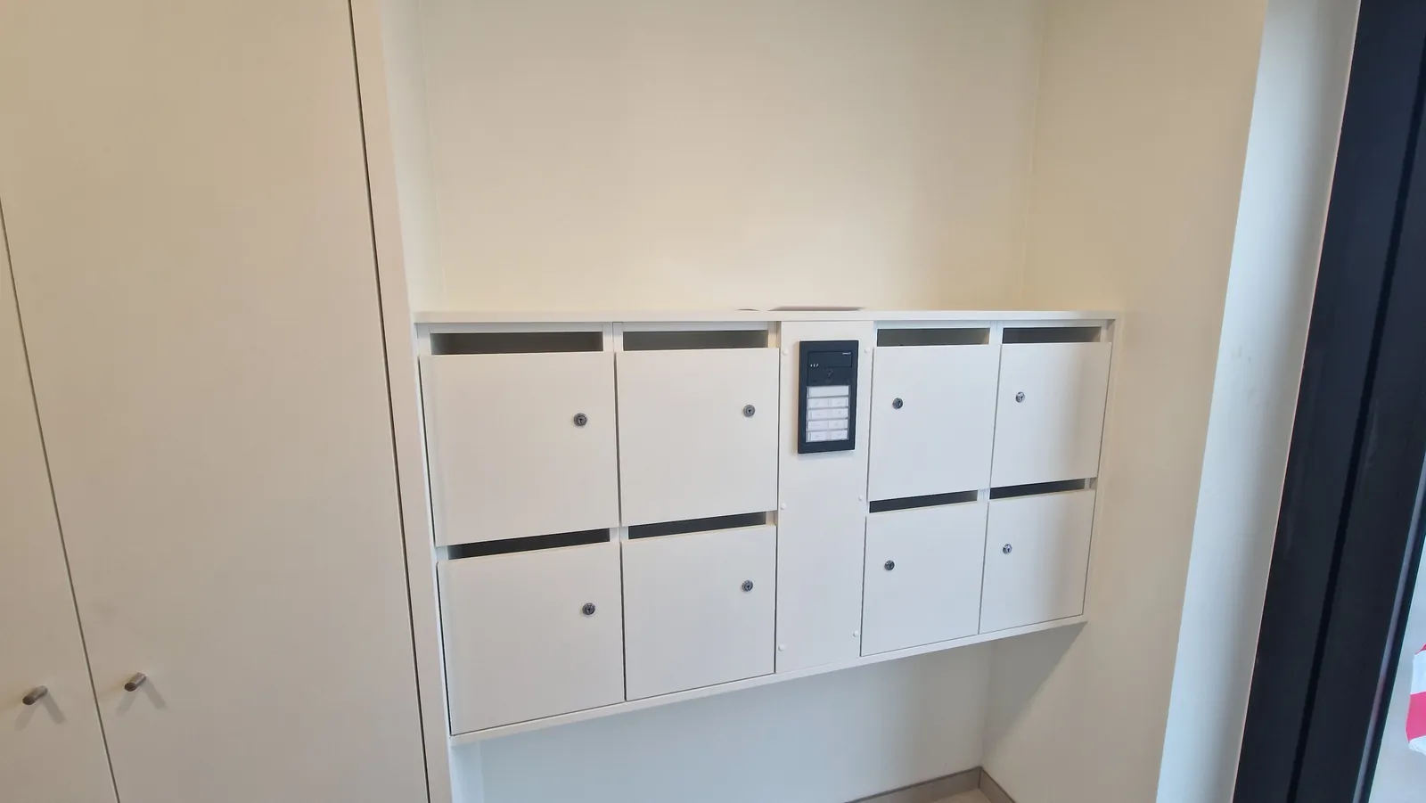 Witte kastenwand met ingewerkte brievenbussen in een inkomhal