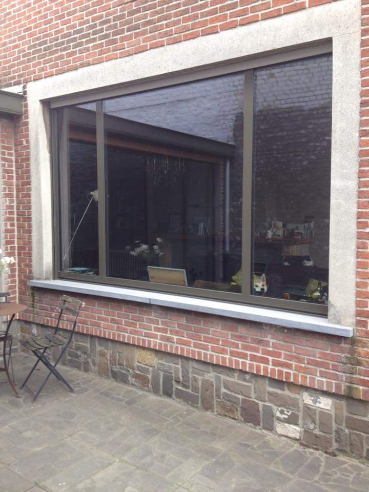 Groot raam met donker schrijnwerk in een bakstenen gevel