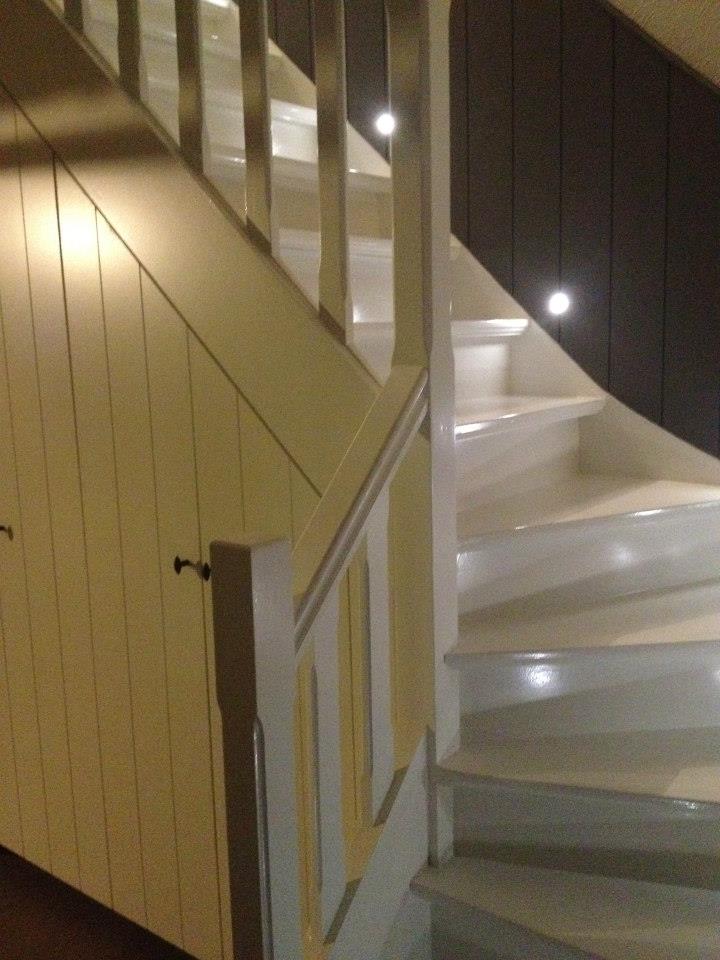 Witte draaitrap met lambrisering langs de wand